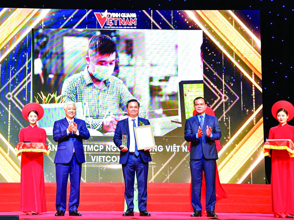 Chủ tịch UBTWMTTQ Việt Nam Đỗ Văn Chiến (bên trái) trao Biểu trưng và Chủ tịch Tổng LĐLĐ Việt Nam Nguyễn Đình Khang (bên phải)  trao Chứng nhận vinh danh cho ông Nguyễn Thanh Tùng - Tổng giám đốc đại diện cho tập thể Vietcombank 