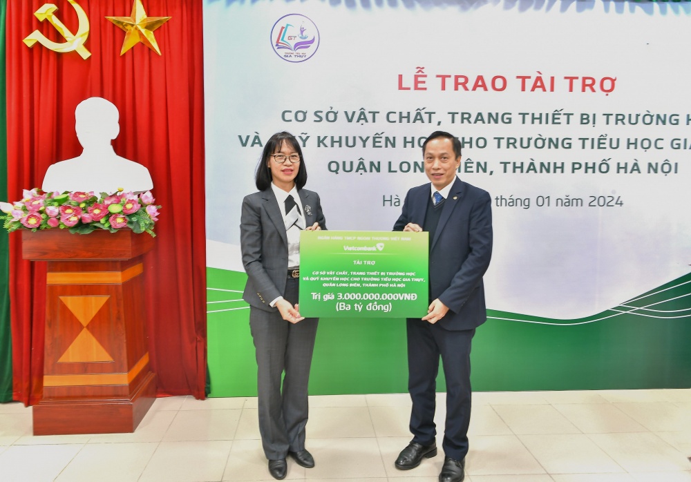 Ông Nguyễn Bá Minh - Giám đốc Vietcombank Chương Dương trao biển tượng trưng số tiền tài trợ ASXH cho cô giáo Bùi Thị Thu Hằng - Hiệu trưởng trường tiểu học Gia Thụy
