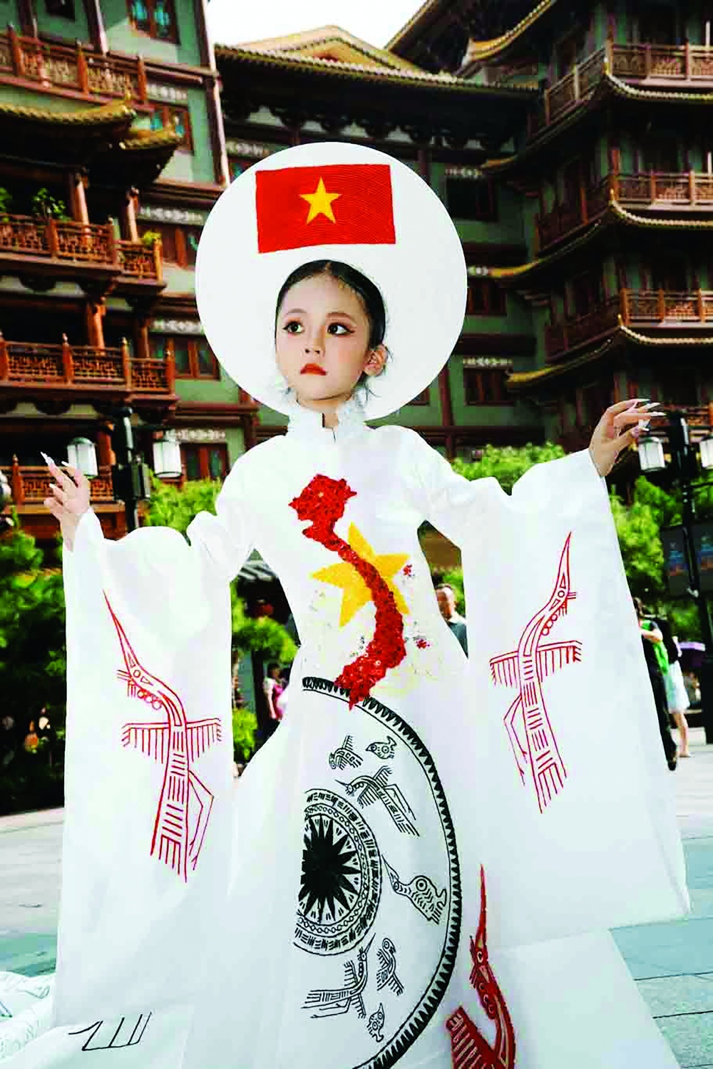 Mẫu nhí Nguyễn Nhật Ánh trong trang phục áo dài với hình ảnh bản đồ và Quốc kỳ Việt Nam ở ngay trung tâm thành phố Quảng Châu, Trung Quốc