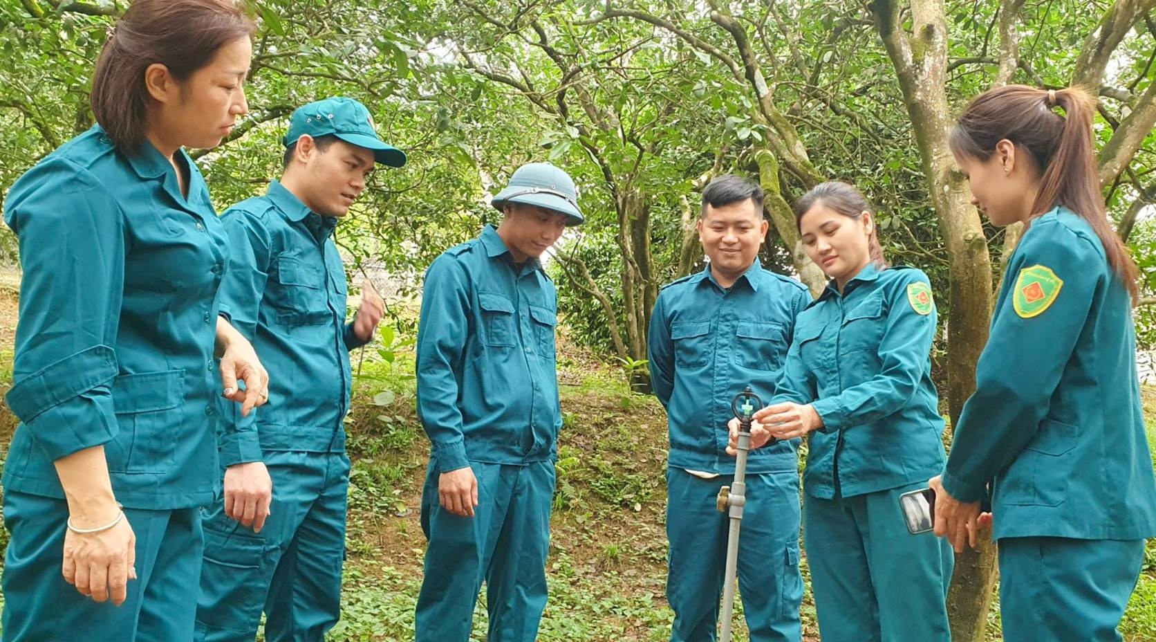 Hoàng Thị Hồng Thương (Thứ 2 bên phải sang) hướng dẫn các thành viên lắp đặt hệ thống tưới Bưởi tự động