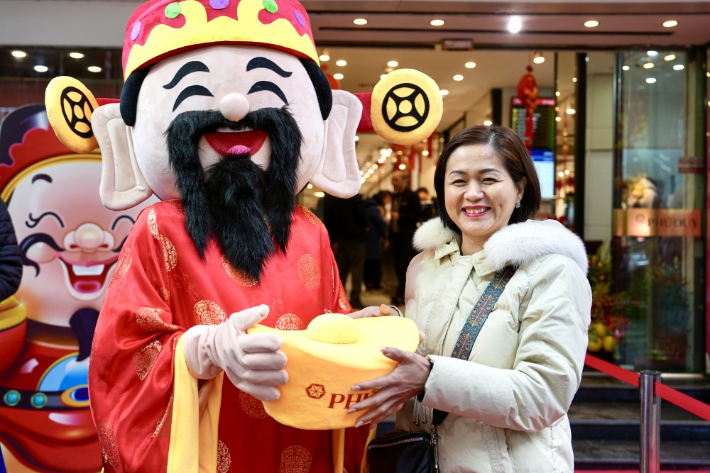 Khách mua hàng chụp ảnh với Thần tài tại cửa hàng Phú Quý