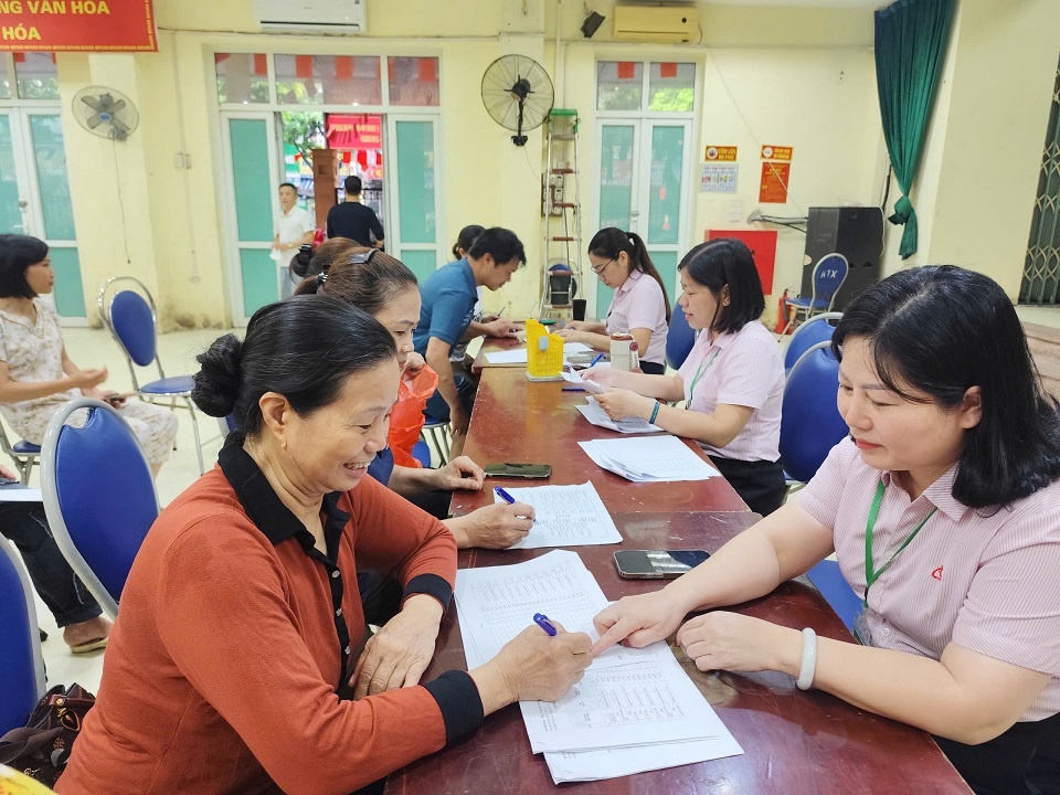 Bà Phạm Thị Liên – Phó Giám đốc NHCSXH Hà Đông đang đối chiếu nợ với người vay tại Nhà văn hóa Mậu Lương phường Kiến Hưng
