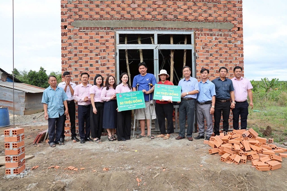Bà Ngô Thuý Hằng - Chủ tịch CĐCS, Phó Giám đốc Chi nhánh NHCSXH thành phố Hà Nội, ông Trương Thanh Dũng - Phó giám đốc Chi nhánh NHCSXH tỉnh Đồng Nai trao tiền hỗ trợ xây nhà cho gia đình ông Phùng Văn Báo