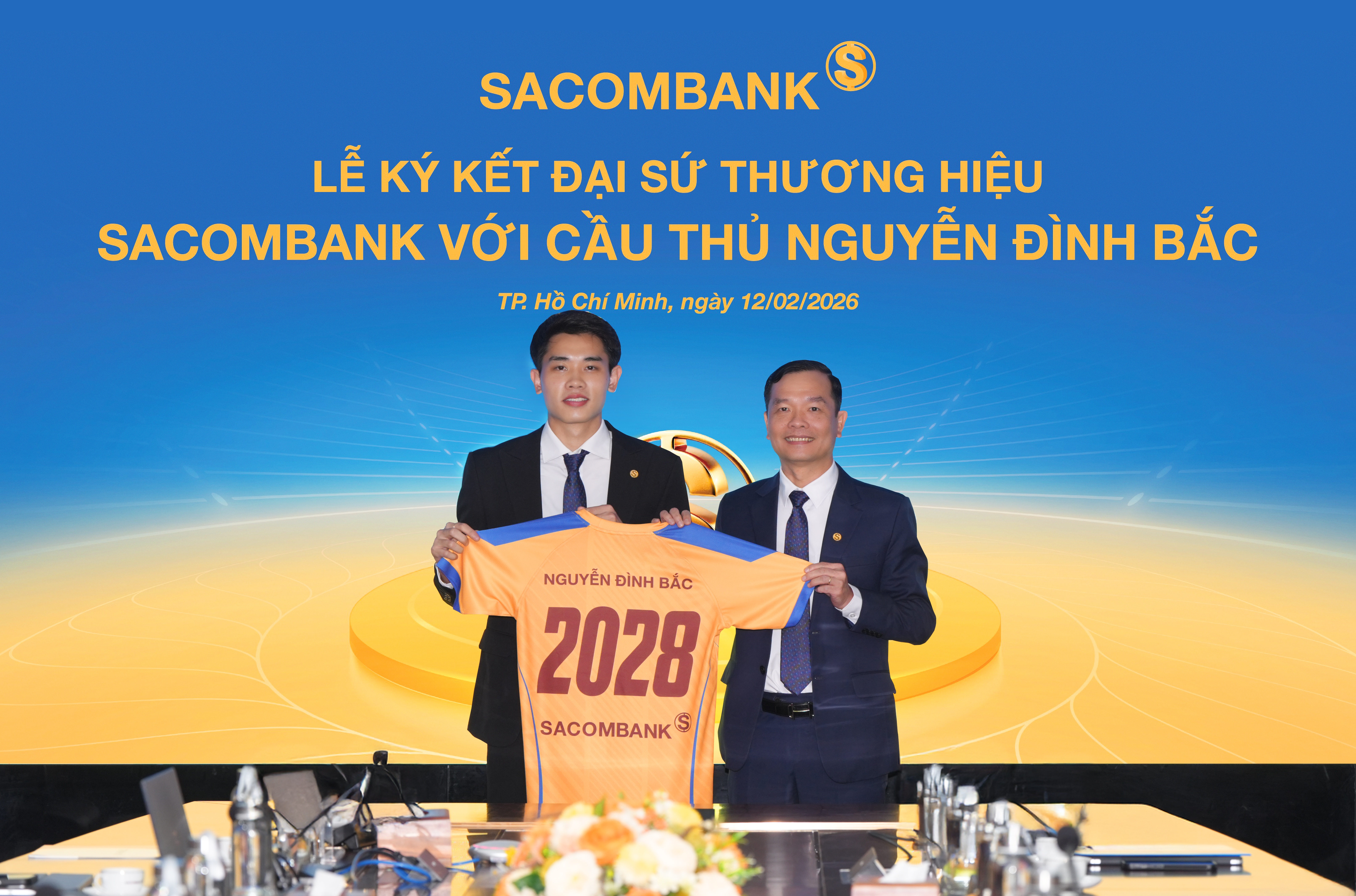 Ông Hà Văn Trung - Phó Tổng giám đốc thường trực SACOMBANK trao trang phục cho Đại sứ thương hiệu Nguyễn Đình Bắc tại buổi lễ ký kết. Ông Hà Văn Trung - Phó Tổng giám đốc thường trực SACOMBANK trao trang phục cho Đại sứ thương hiệu Nguyễn Đình Bắc tại buổi lễ ký kết.
