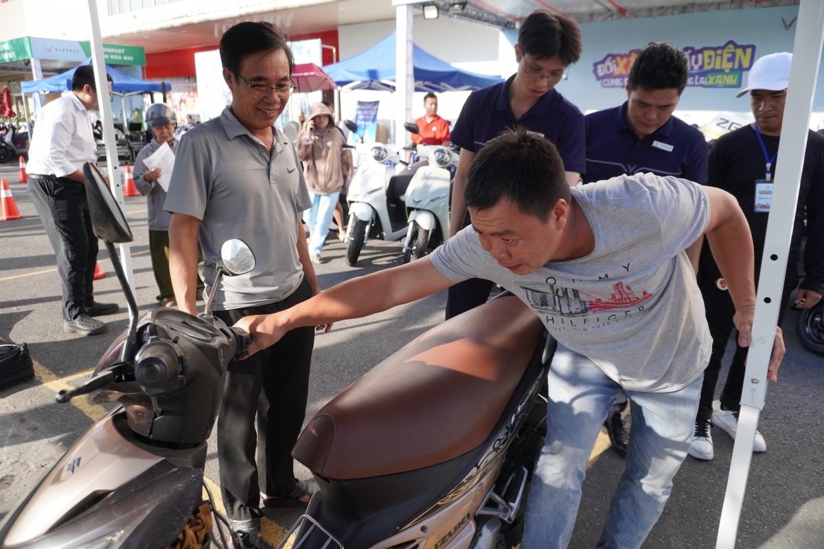 Ông Thông (bìa trái) mang xe máy xăng cũ đến định giá để đổi lấy VinFast Evo Grand Lite Ông Thông (bìa trái) mang xe máy xăng cũ đến định giá để đổi lấy VinFast Evo Grand Lite
