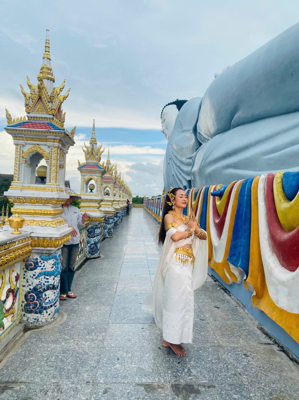 Em bé trong trang phục truyền thống của dân tộc Khmer chụp ảnh lưu niệm cùng tượng Phật nằm chùa Som Rong Em bé trong trang phục truyền thống của dân tộc Khmer chụp ảnh lưu niệm cùng tượng Phật nằm chùa Som Rong